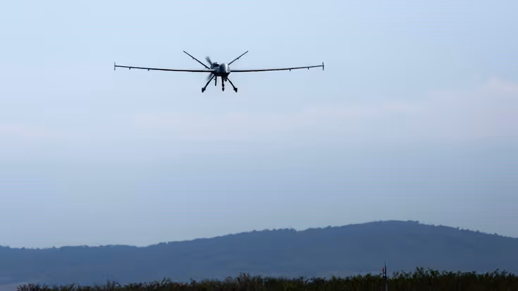 Een MQ-9 Reaper in de lucht in Roemenië met op de achtergrond een berg