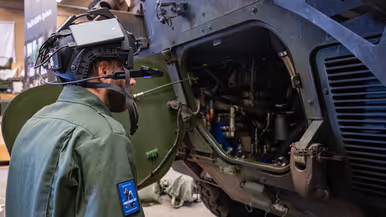 Een monteur met een camera op zijn helm bij een voertuig. 