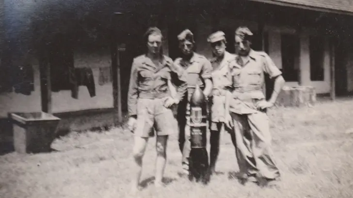 Oude foto: 4 militairen poseren met een vliegtuigbom.