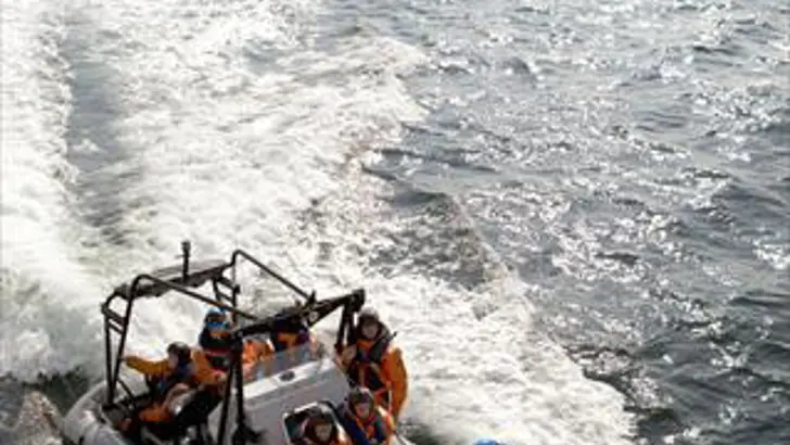 Op de voorgrond een RHIB met op de achtergrond een schip.