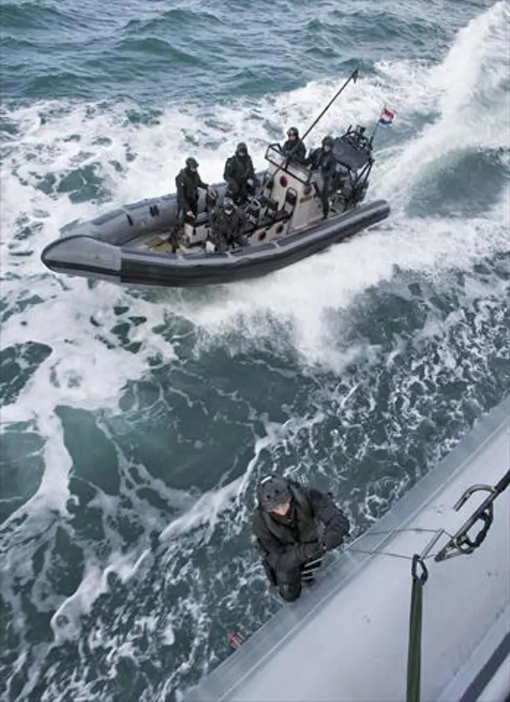 Een boardingteam in een RHIB komt aanvaren bij een schip.