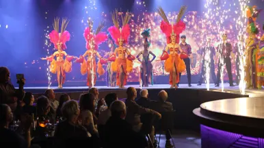 Danseressen, dansers en vuurwerk op een podium voor publiek.