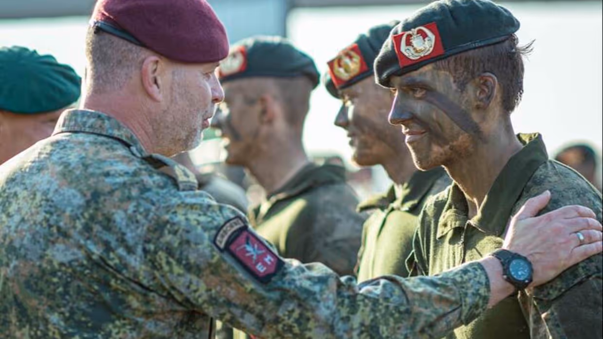 Hoge militair legt hand op schouder andere militair ter felicitatie bij ceremonie.