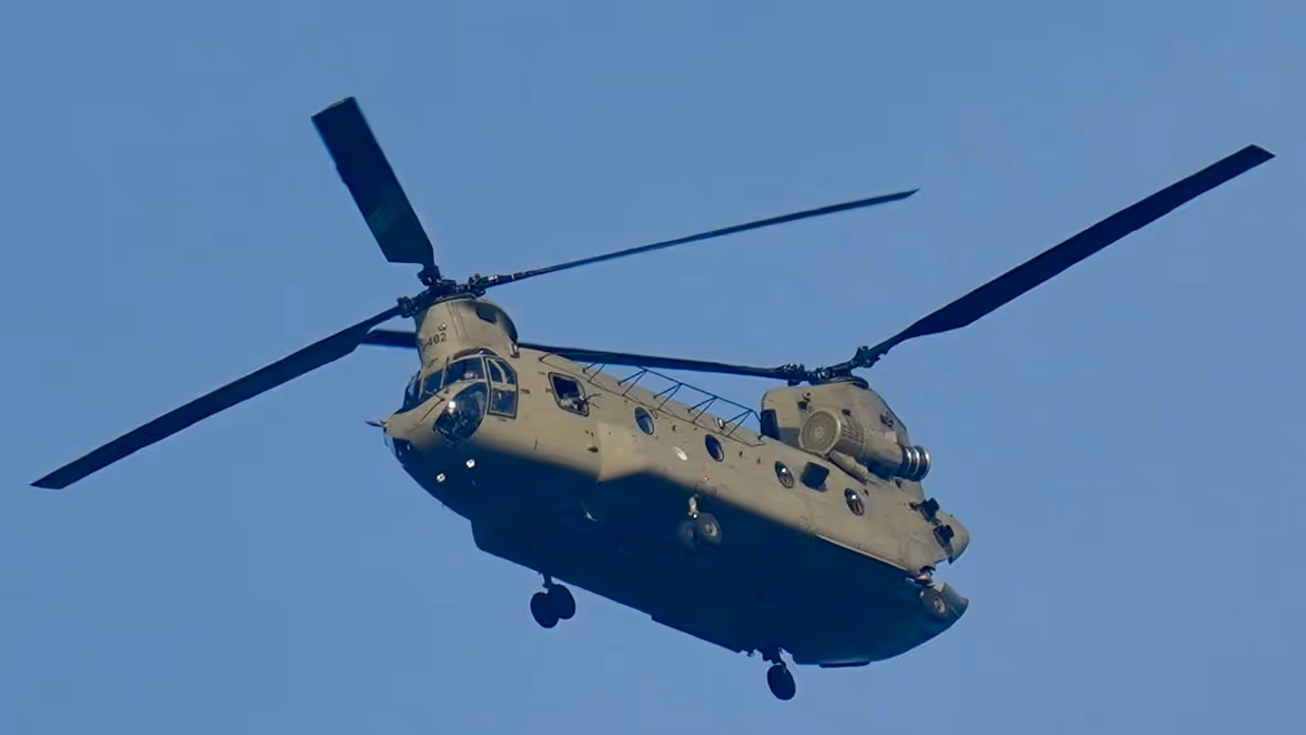 Een Chinook-helikopter vliegt in de blauwe lucht. 
