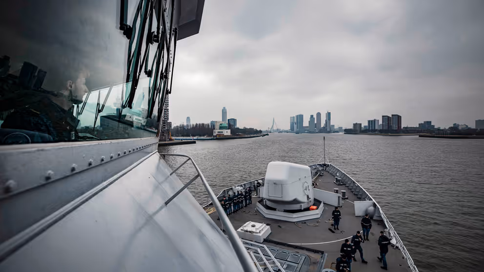 Marineschip vaart haven van Rotterdam binnen.