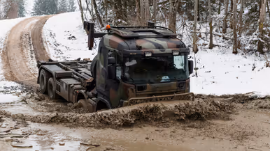 Een truck rijdt in de winter door sneeuw en modder.