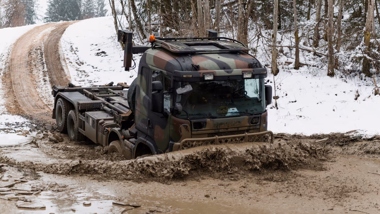 Een truck rijdt in de winter door sneeuw en modder.