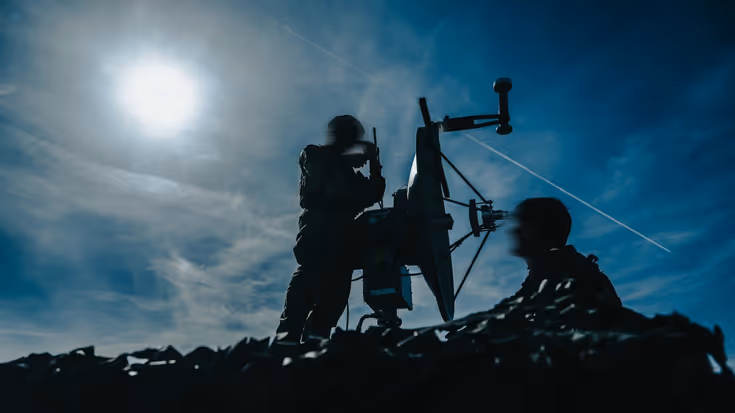 Silhouetten van militairen met een wapen.
