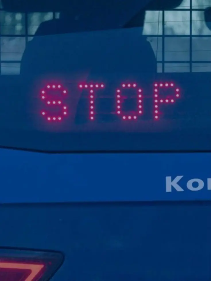 Een stopteken achter de achterruit van een Marechaussee-auto.