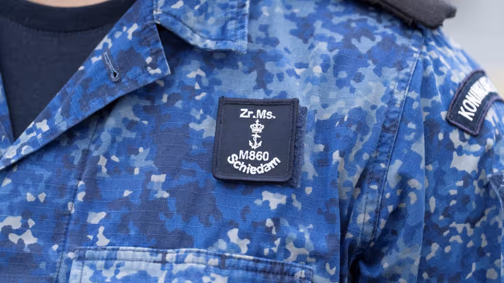 Het embleem van SNMCMG1 op het uniform van een militair. 