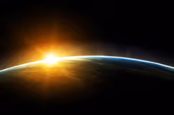 De aarde met een zonnestraal net boven de planeet, gezien vanuit de ruimte.