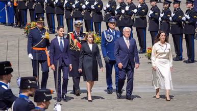 Minister-president Rob Jetten loopt samen met de bondspresident van Duitsland, diens vrouw en de burgemeester van Amsterdam door een erehaag van militairen gekleed in ceremonieel tenue. Vlak achter hen lopen ook drie militairen in ceremonieel tenue.
