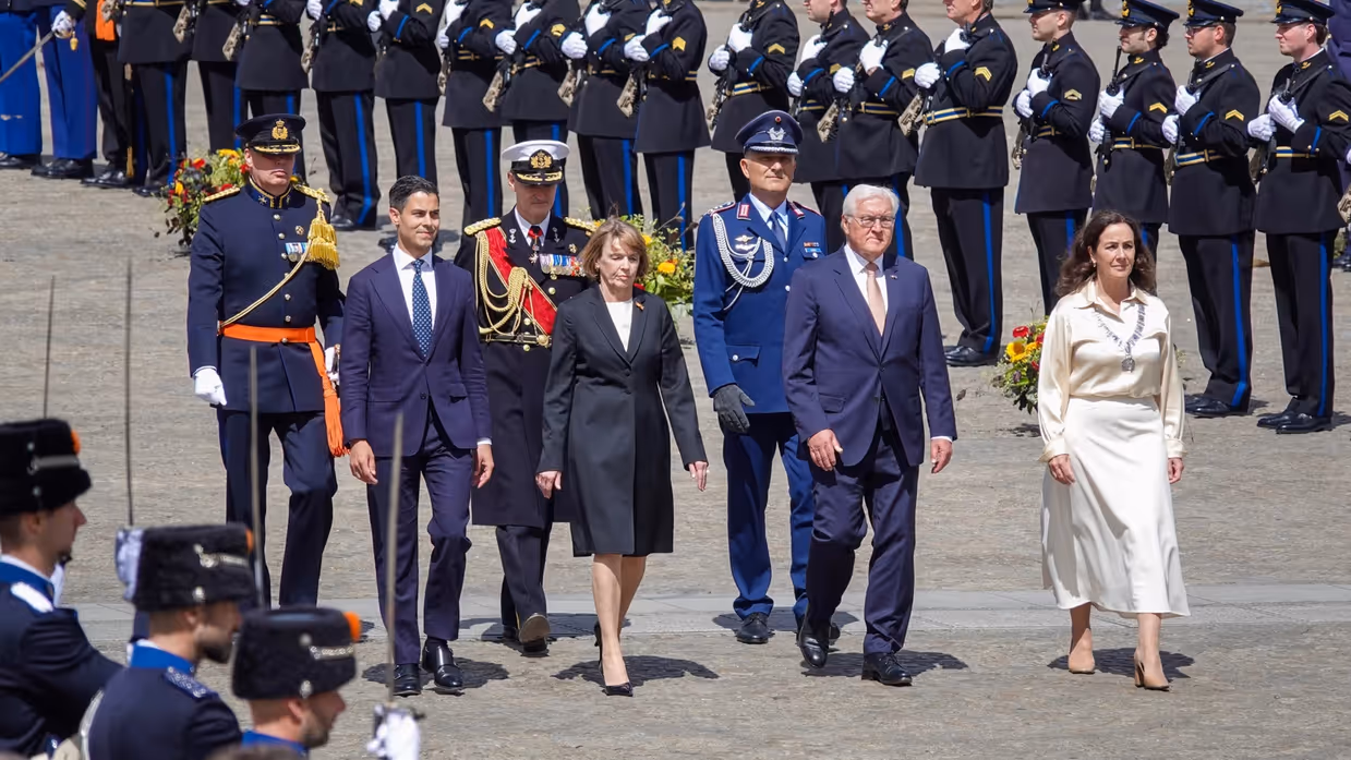 Minister-president Rob Jetten loopt samen met de bondspresident van Duitsland, diens vrouw en de burgemeester van Amsterdam door een erehaag van militairen gekleed in ceremonieel tenue. Vlak achter hen lopen ook drie militairen in ceremonieel tenue.