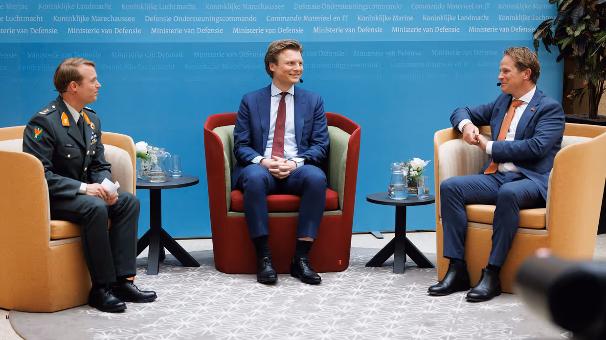 Brekelmans en Tuinman zitten in gele stoelen terwijl ze worden geïnterviewd door een militair 