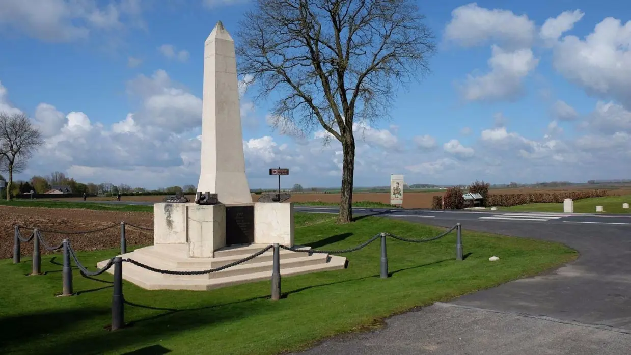 Een hoog wit monument met een obelisk, omringd door groen gras, bomen en een heldere hemel. (Foto: Tripadvisor)