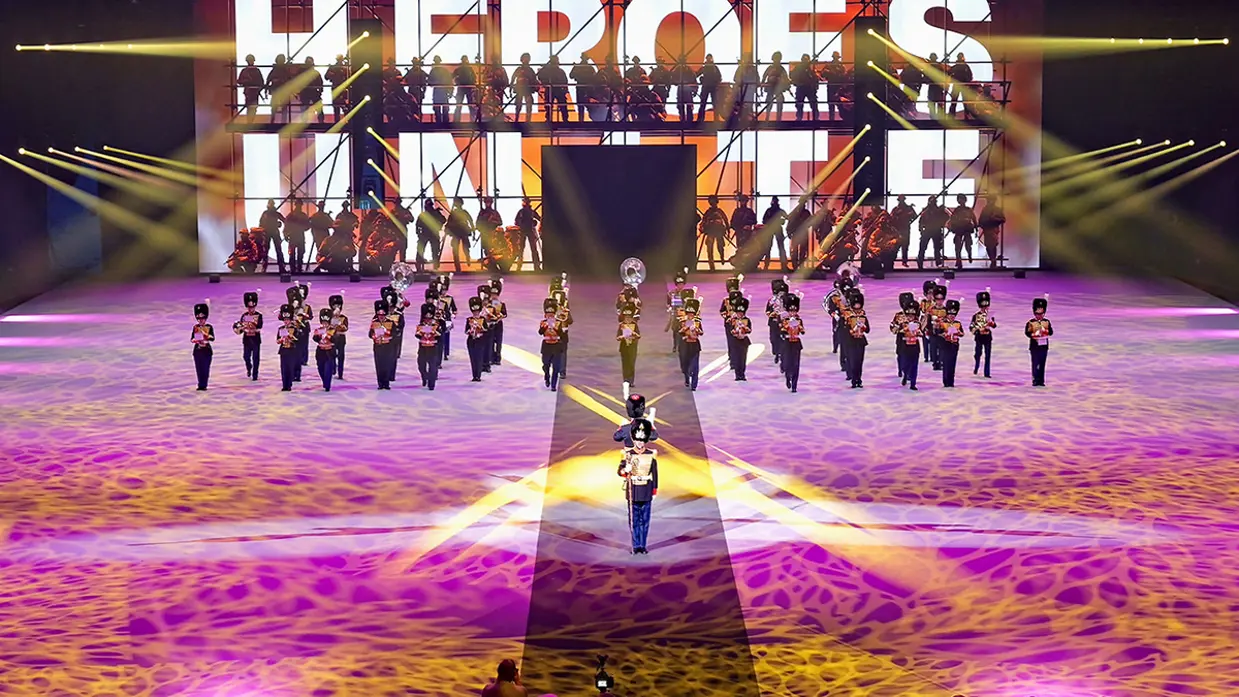 De KMKJWF tijdens de Nationale Taptoe. Op de achtergrond het woord: "heroes".