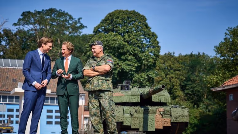 Vertrekkend minister Ruben Brekelmans en staatssecretaris Gijs Tuinman praten met CDS generaal Onno Eichelsheim. Op de achtergrond staat een Leopard-tank  