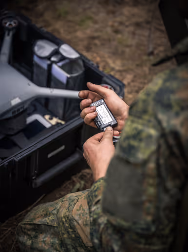 Militair controleert een dronecomponent tijdens voorbereiding in het veld. 
