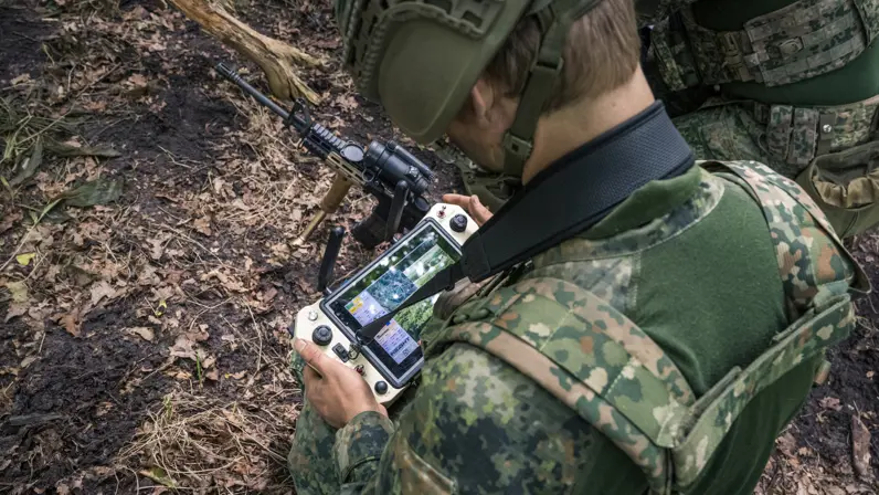 Militair bedient een drone via een controller en scherm in het veld. 