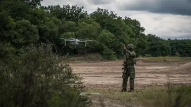 Een militair kijkt naar een drone die landt. 