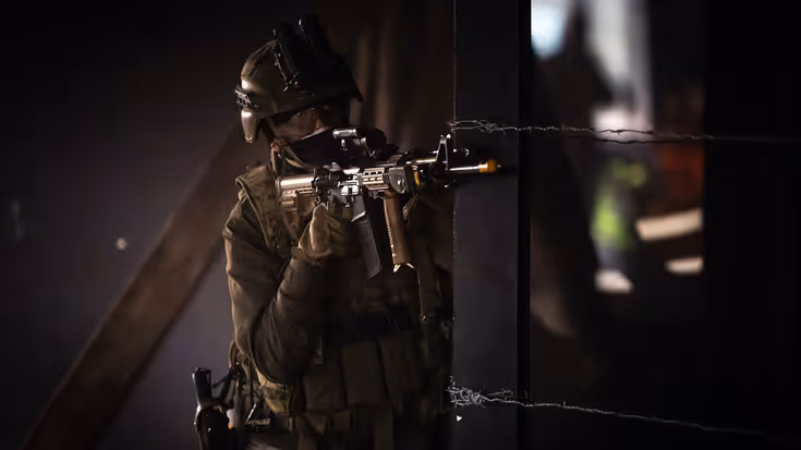 Militair in half duister richt geweer om de hoek.