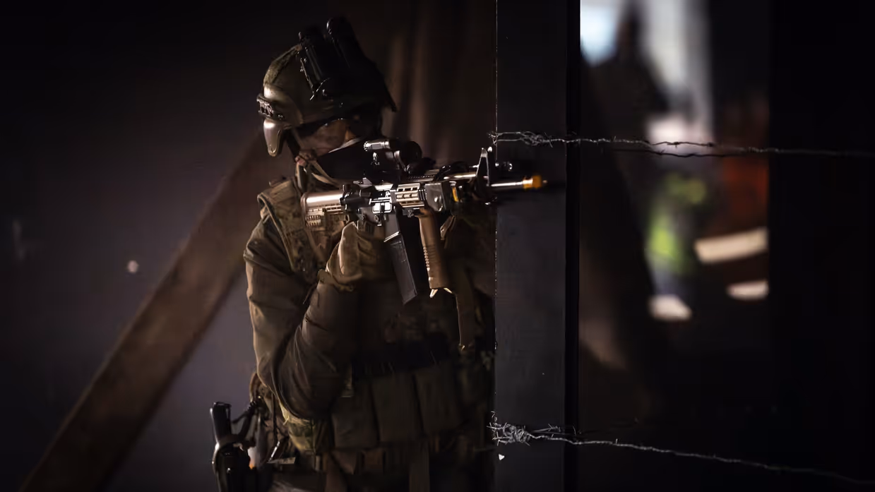 Militair in half duister richt geweer om de hoek.