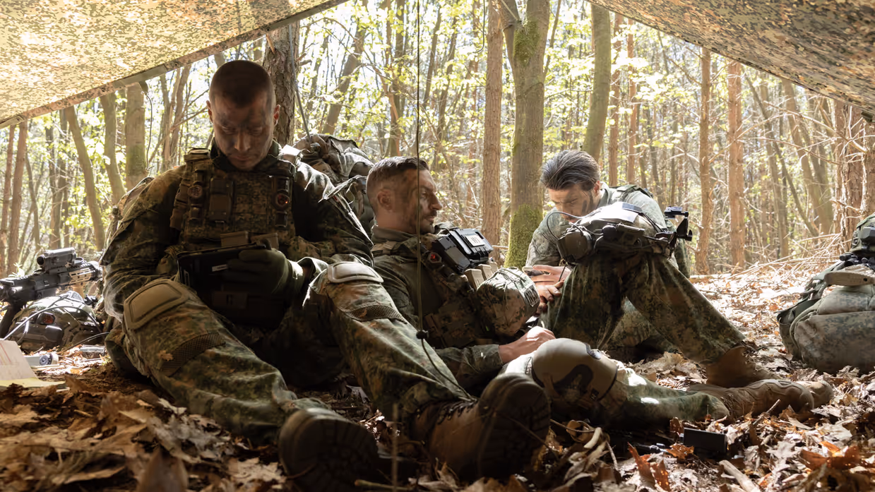 Militairen rusten en bereiden zich voor onder een gecamoufleerd schuilzeil.