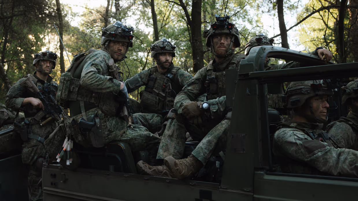 Militairen van 11 Luchtmobiele Brigade zitten met gevechtsuitrusting in een voertuig.