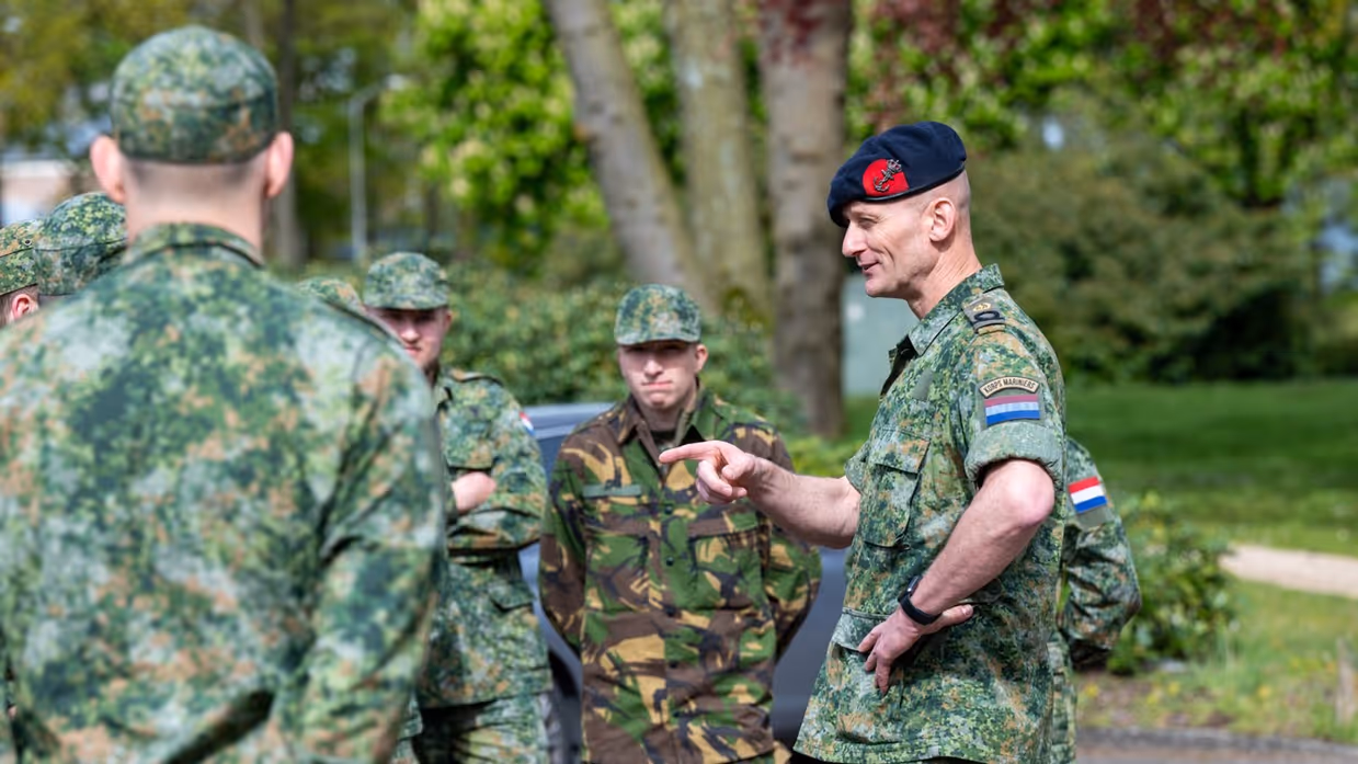 Groepje militairen luistert naar andere militair die spreekt.
