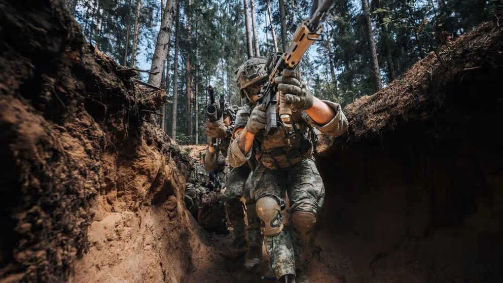 Gewapende militairen in een loopgraaf.