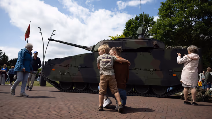 Kind speelt voor geparkeerde CV90-infanteriegevechtsvoertuig.