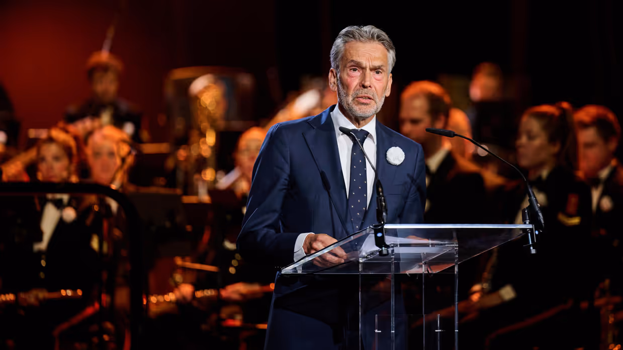 Premier Schoof spreekt de aanwezigen in de Koninklijke Schouwburg toe door een microfoon.