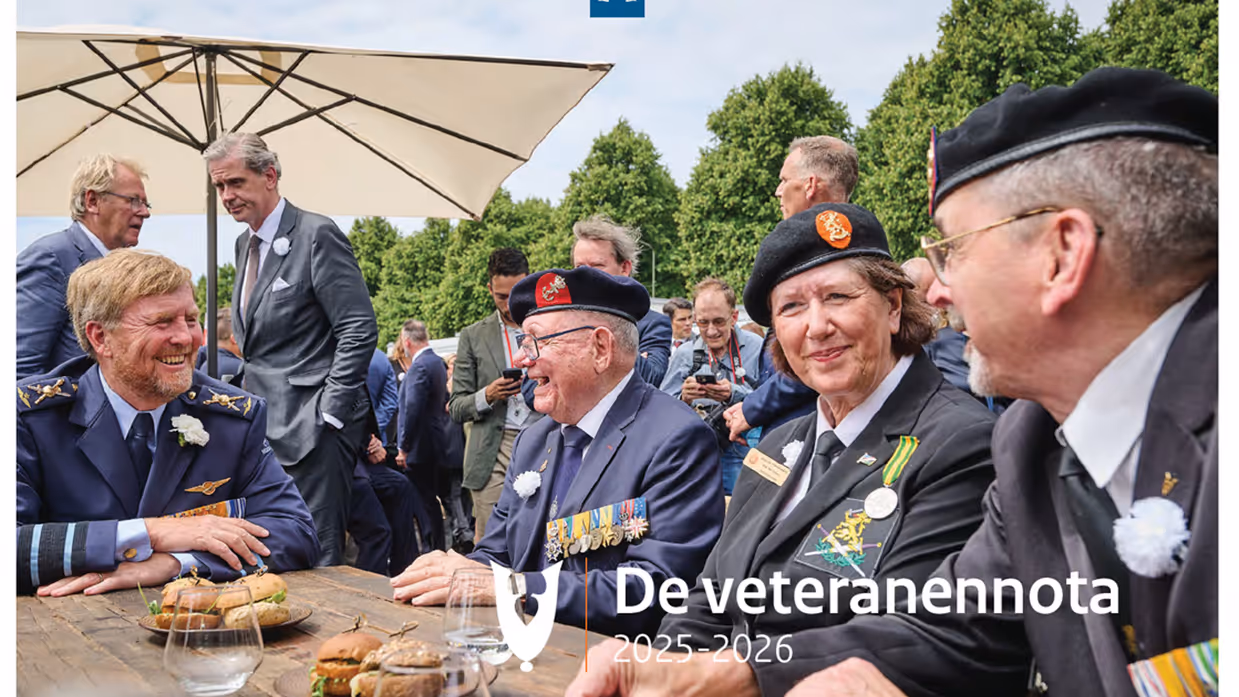 Drie veteranen in informele sfeer aan een buitentafel in gesprek met koning Willem-Alexander. Op de achtergrond bomen en pratende mensen. Over de foto heen staat de tekst ‘De veteranennota 2025-2026’.