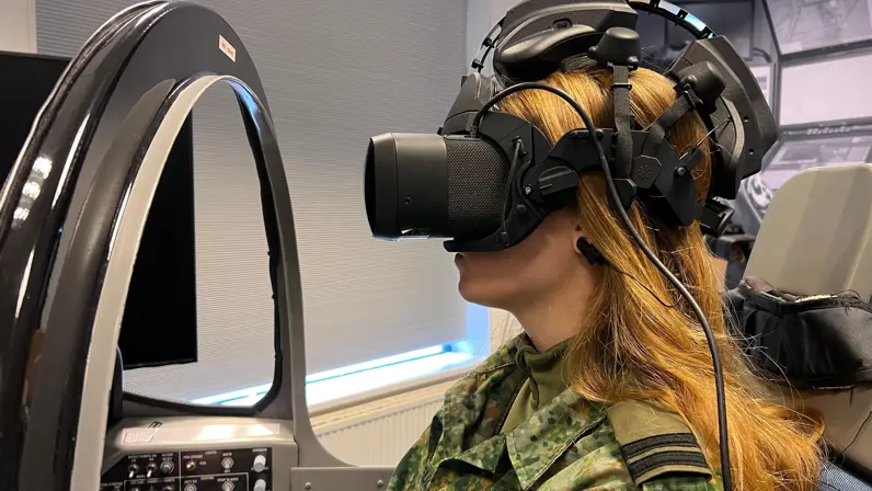 Vrouwelijke militair met VR-bril op in simulator. 