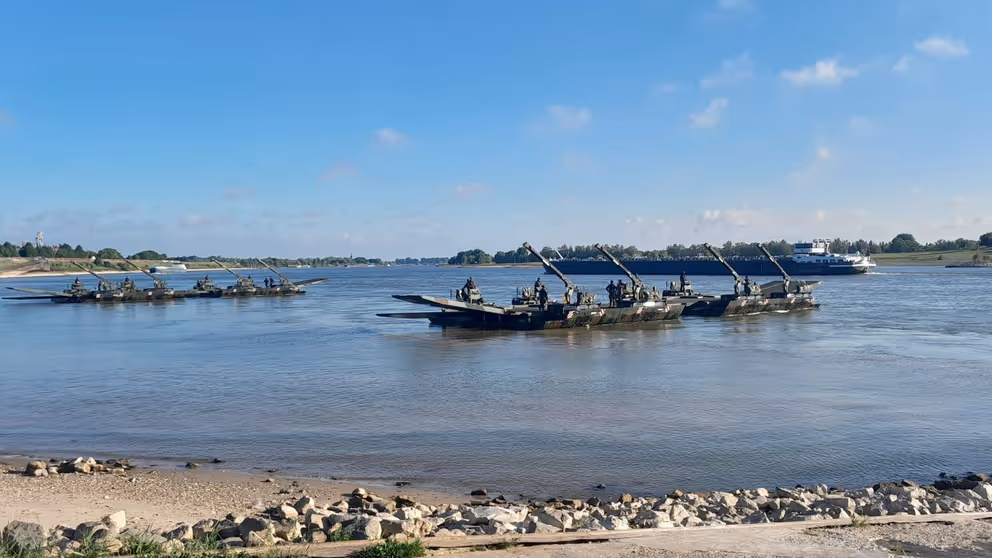 Militairen staan op pontons in een rivier.