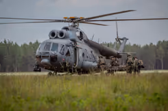 Militairen brengen een militair op een brancard naar een helikopter.
