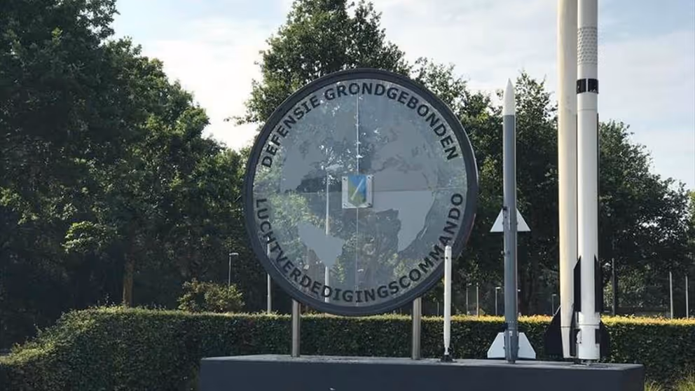 Logo Defensiegebonden Luchtverdedigingscommando, met daarnaast twee raketten
