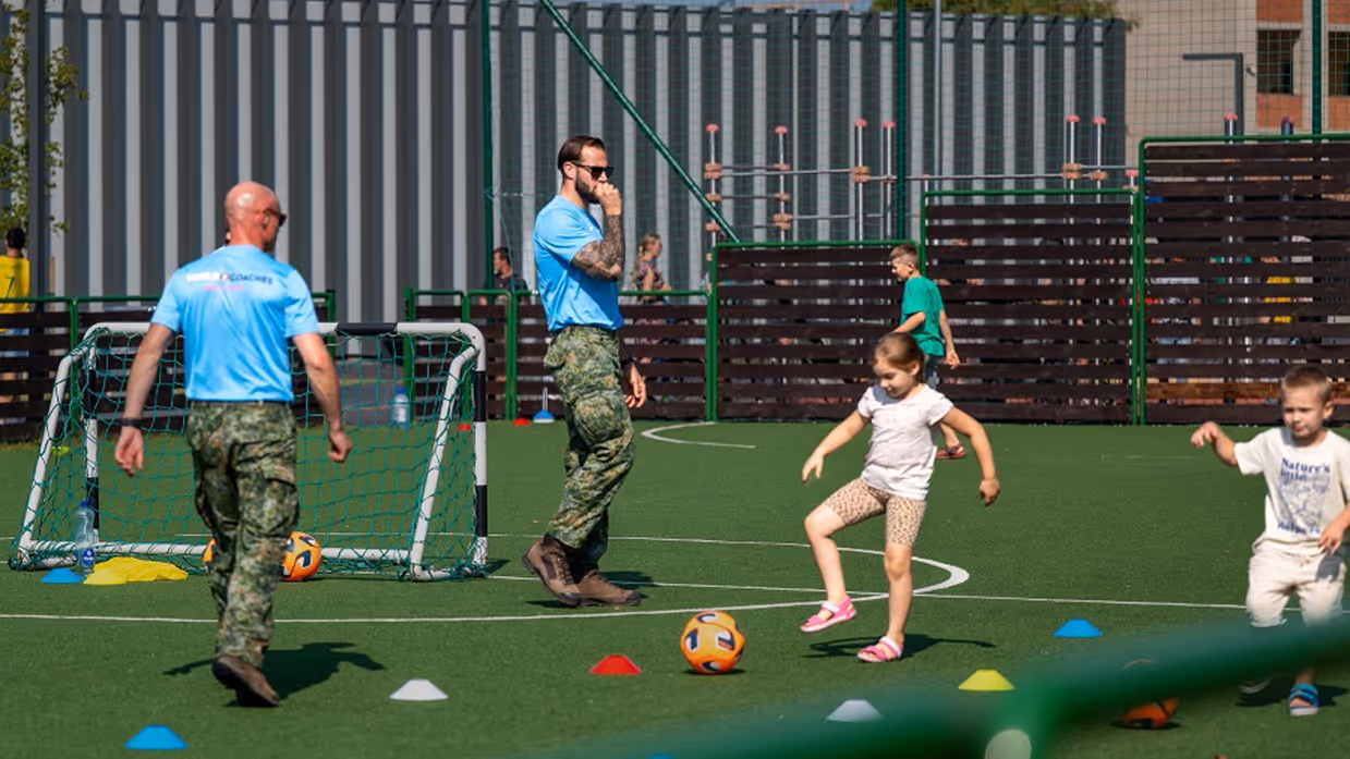 Militairen voetballen met kinderen.