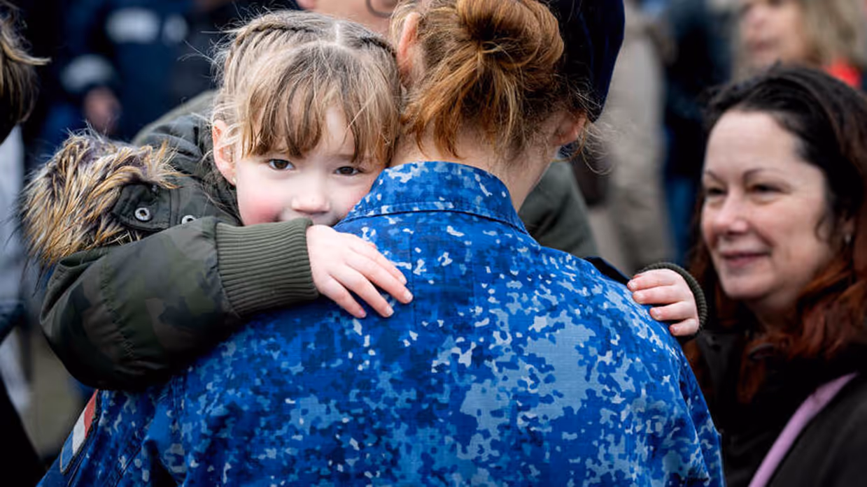 Militair knuffelt kind.