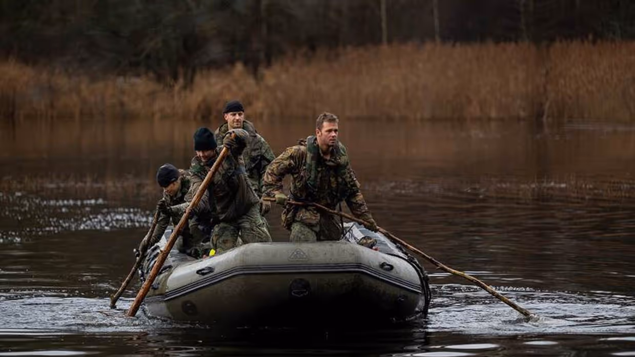 Militairen peddelen in rubberboot.