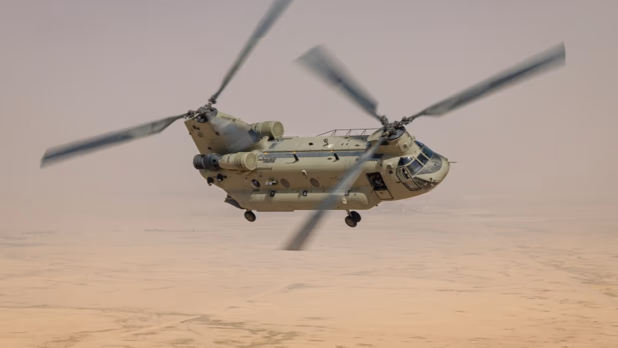 Chinook transporthelikopter vliegt in de lucht boven woestijn.