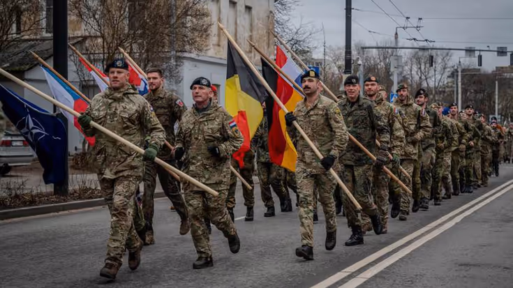 Marcherende militairen met vlaggen van NAVO-bondgenoten.