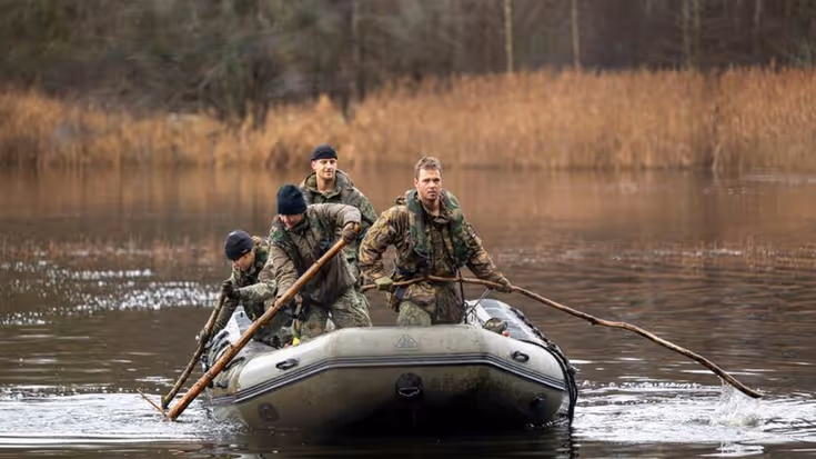 Militairen peddelen in rubberboot.