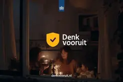 'Denk vooruit' staat op een foto genomen door een raam van 2 vrouwen en een kind die alleen kaarsjes aan hebben.