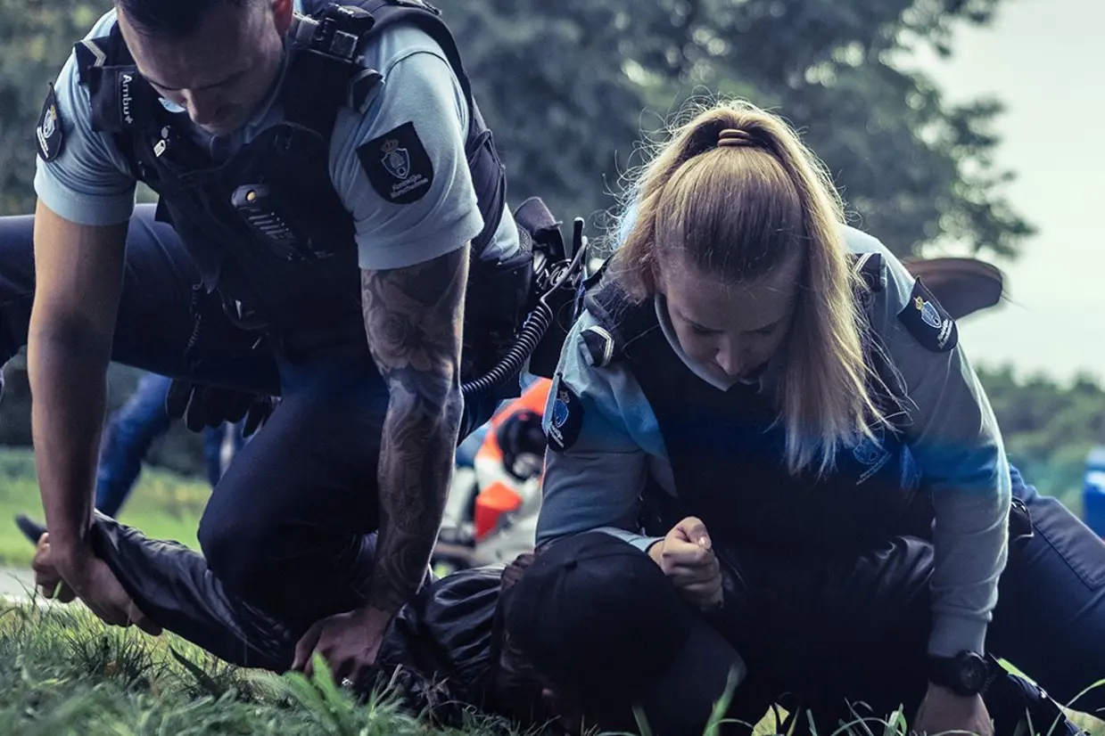 Vrouwelijke en mannelijke marechaussee houden een persoon tegen de grond.