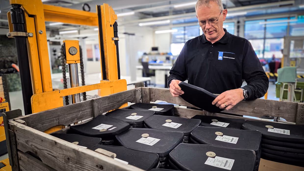 Bert staat achter een bak ballistische platen en doet een visuele inspectie