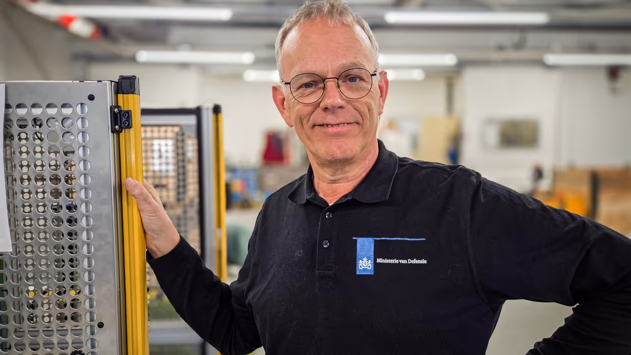 “Het is erg leuk werk en ik ben er ook trots op.”  Alt: Een portretfoto van Bert, coördinator van de veldmaskerwerkplaats van het KPU-bedrijf. 