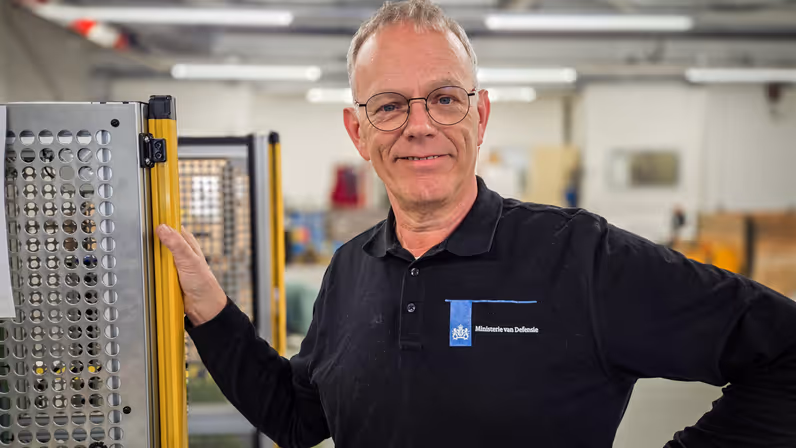 “Het is erg leuk werk en ik ben er ook trots op.”  Alt: Een portretfoto van Bert, coördinator van de veldmaskerwerkplaats van het KPU-bedrijf. 