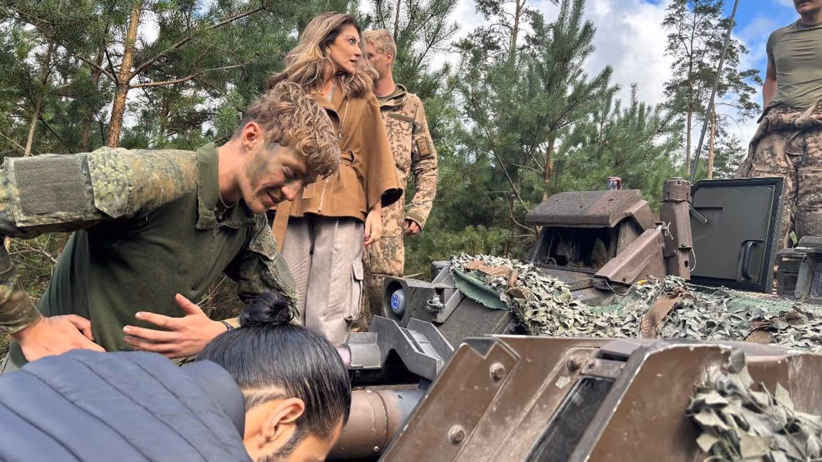 Dilan Yesilgöz tussen militairen bovenop militair voertuig. 