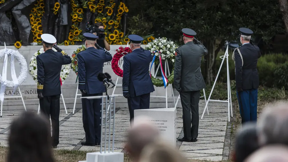 Militairen salueren bij een herdenking.